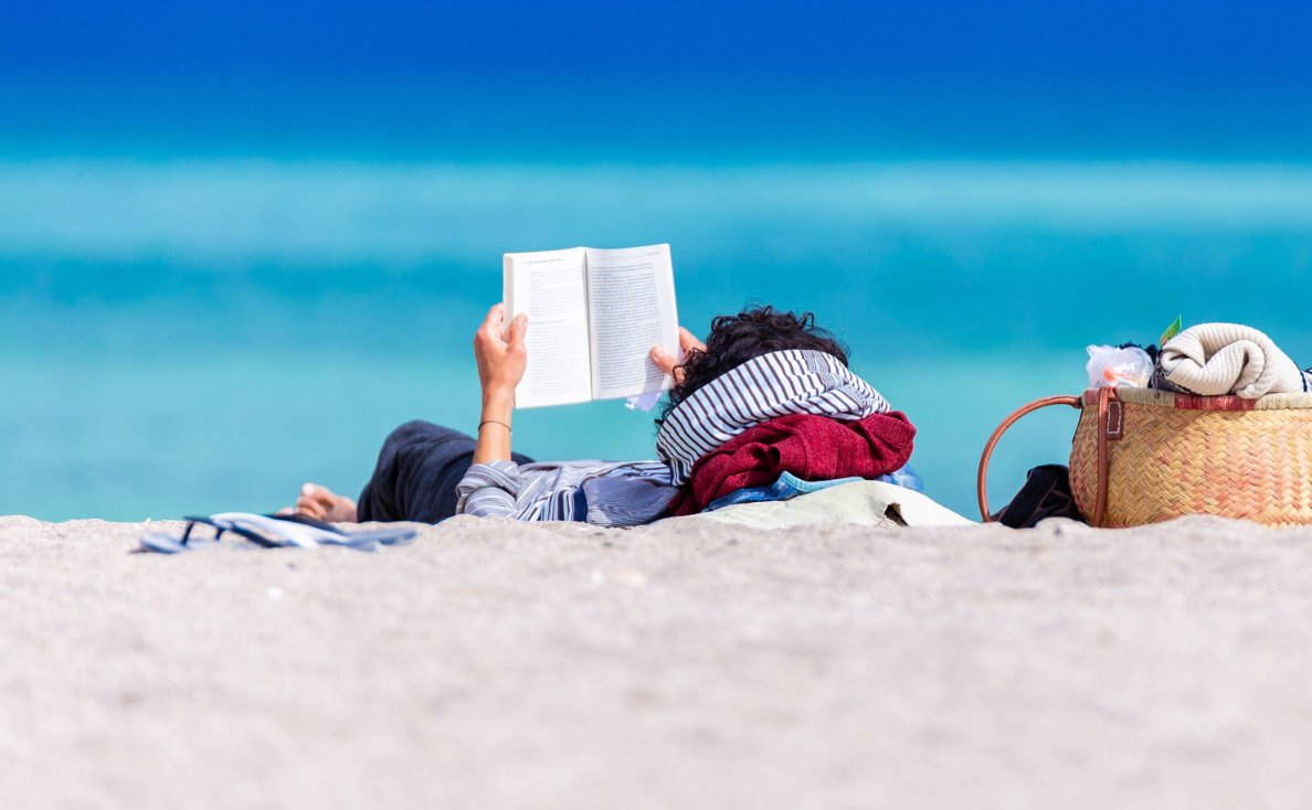 Photo of person reading a book on the beach